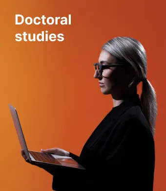 Doctoral studies at KTU – fall in love with science and with yourself. A young KTU PhD student with glasses, holding a laptop and working on it, against a vibrant orange background.